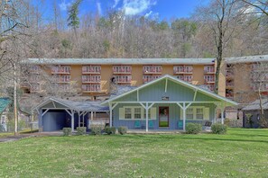 A hotel with a covered lobby area, outdoor seating, and a building with multiple balconies in the background. - Aspen House Walk to Downtown Gatlinburg River View + Free Attraction Tickets (Gatlinburg)