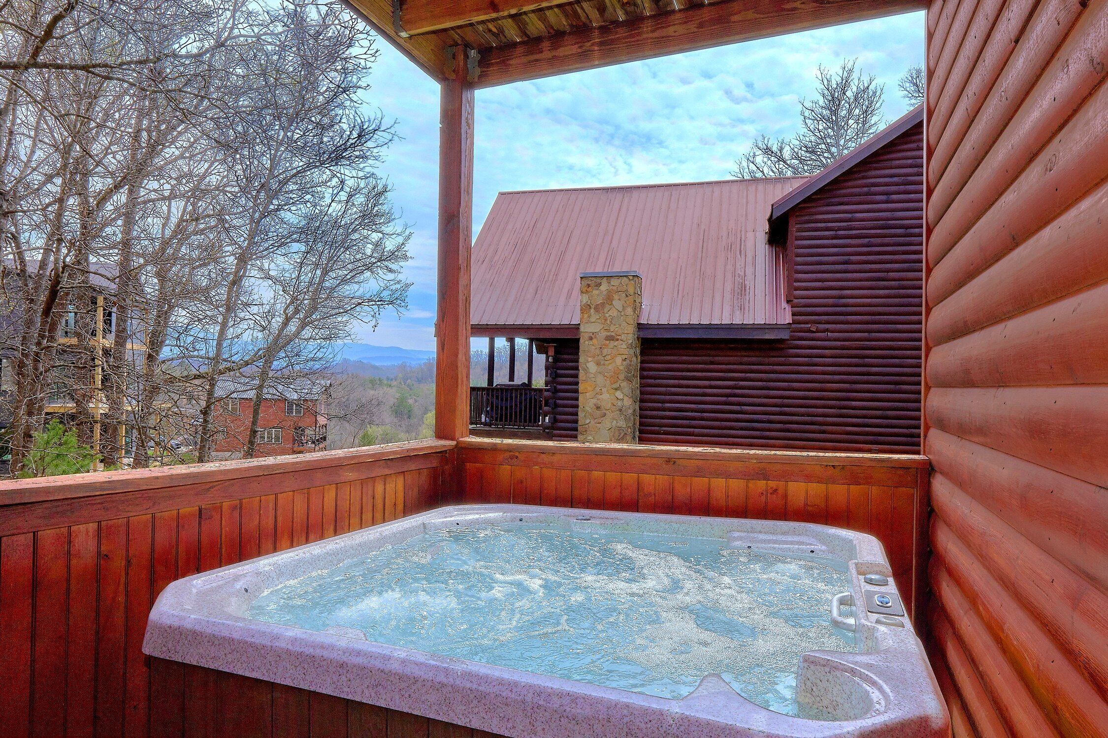 A hot tub in a wooden deck area with a view of a house and trees.