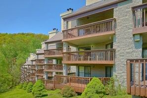 A row of multi-story buildings with balconies, stone facades, and a green landscape. - Our Mountain Home | Smoky Mtn Views, Gatlinburg, Fireplace + Free Attraction Tickets (Gatlinburg)