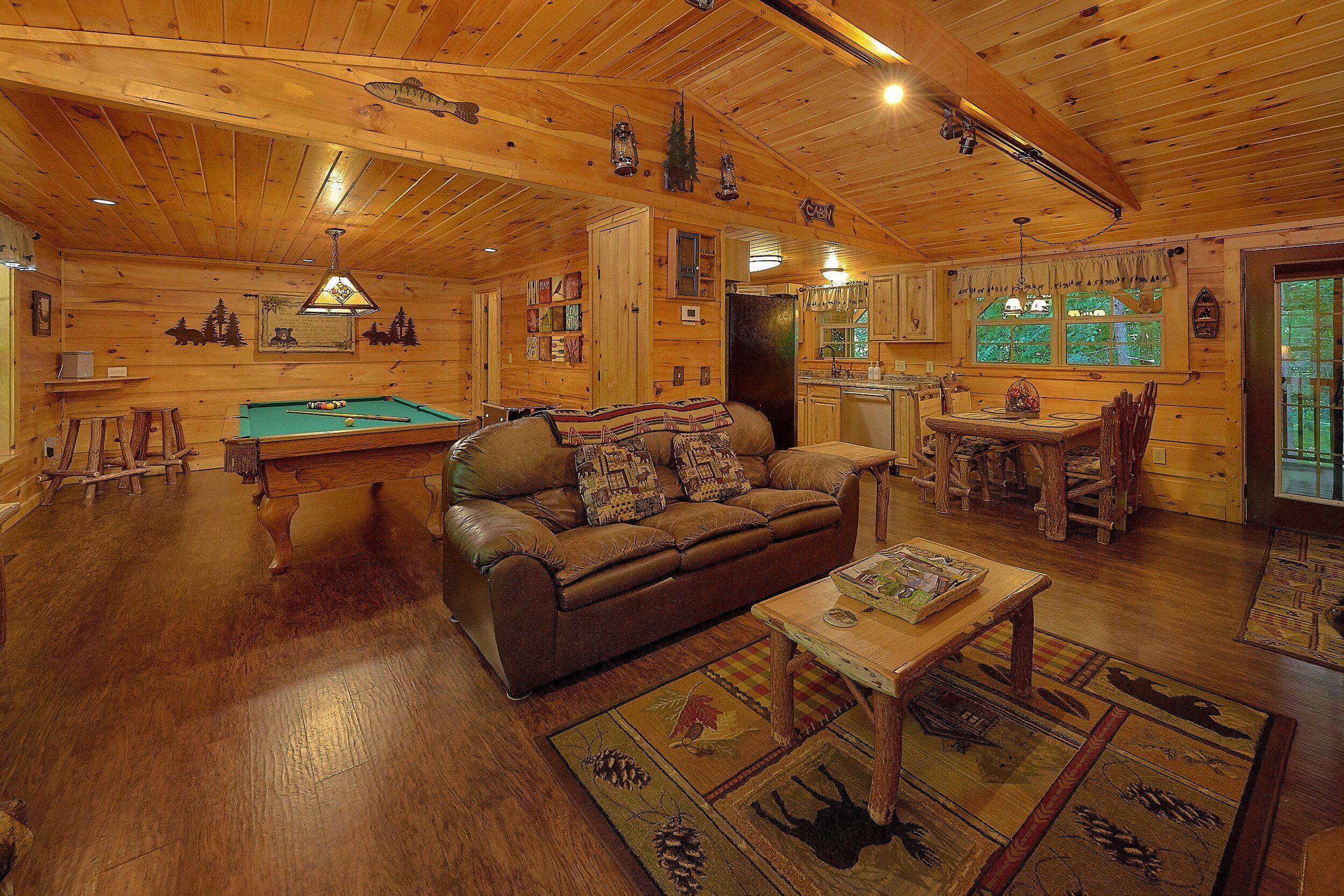 Ein gemütliches Blockhaus-Interieur mit Billardtisch, Ledersofa und Essbereich.