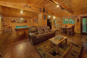 A cozy cabin interior with a pool table, a leather sofa, and a dining area. - Webb Creek Hideaway | Hot Tub, Fire Pit, Gatlinburg, Pet Friendly + Free Attraction Tickets (Gatlinburg)