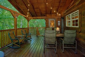 Eine HolzdTerrasse mit Schaukelstühlen und einem Tisch, umgeben von einem Holengeländer.