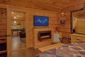 Ein Holzblockhaus-Interieur mit Fernseher, Kamin und einem Bett.