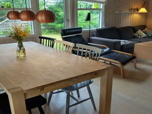 A modern living room with a wooden dining table, black chairs, a grey sofa, and a large window with a view of greenery. - "Meike" - 750m from the sea by Interhome (Bindslev)