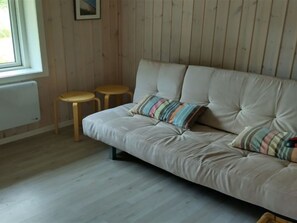 A room with a sofa, two wooden stools, a radiator, and a window. - "Meike" - 750m from the sea by Interhome (Bindslev)