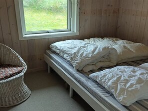 A small, cozy room with a single bed, a bench, and a wicker chair. - "Meike" - 750m from the sea by Interhome (Bindslev)