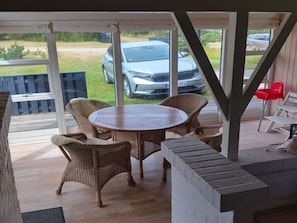 A covered outdoor seating area with wicker furniture and a view of a parked car. - "Meike" - 750m from the sea by Interhome (Bindslev)