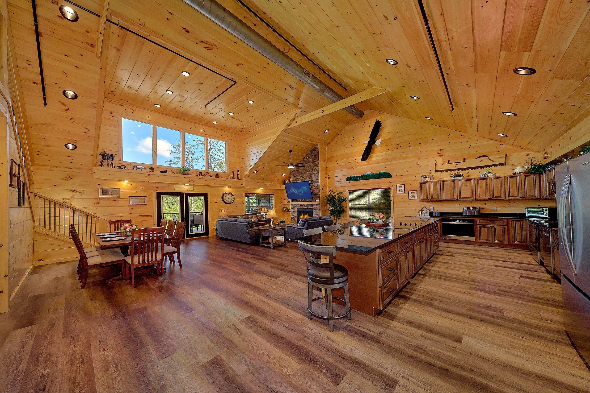 A spacious log cabin interior with a large dining area, a living room, and a kitchen.