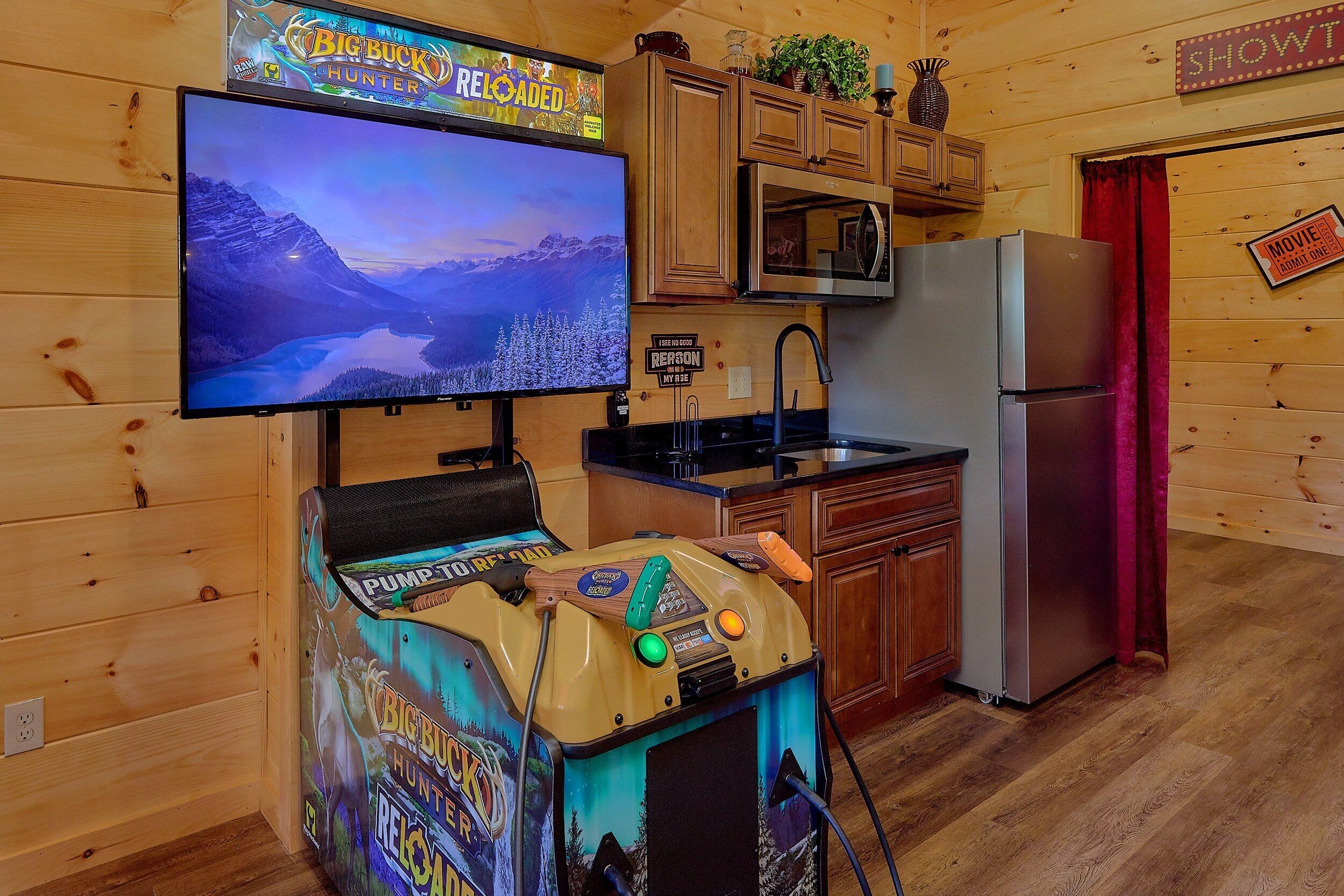 A room with a television displaying a game, a kitchen area, and a sign indicating a movie theater.