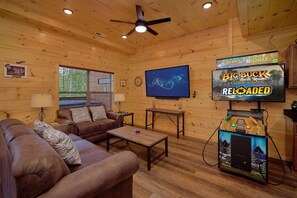 Ein gemütliches Blockhaus-Interieur mit einer braunen Ledersofa, einem Couchtisch und einem Fernseher, der ein Spiel zeigt.