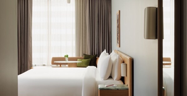 Une chambre d’hôtel avec un grand lit, une table de chevet avec une lampe, une petite table avec une plante et un canapé.
