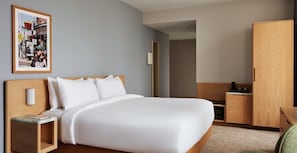 Une chambre d’hôtel avec un grand lit, une table de chevet, une armoire et un tableau encadré au mur.