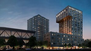 Un immeuble moderne de grande hauteur, doté d’une conception architecturale unique, avec une vaste façade en verre et de nombreux balcons.