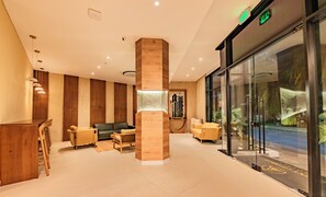 A lobby with a reception desk, seating area, and a glass wall with a view.
