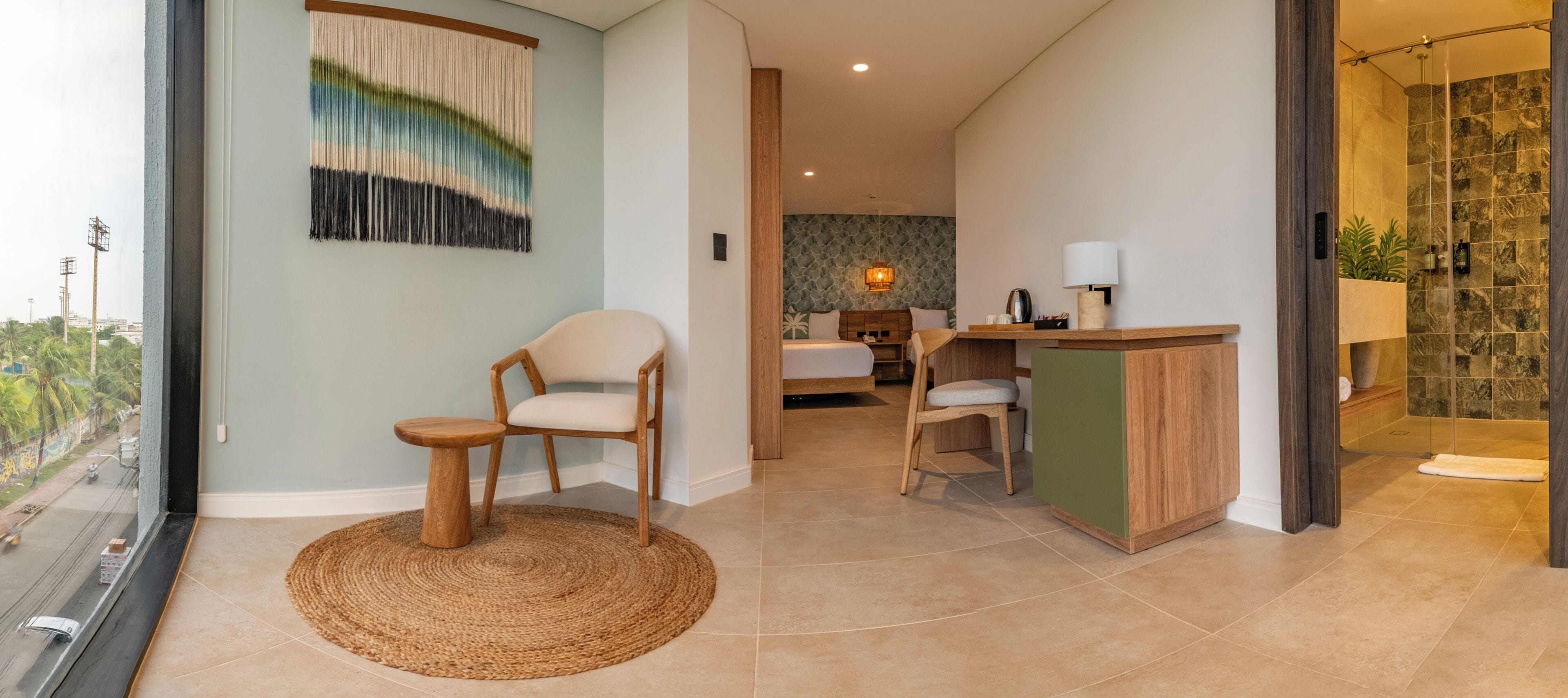 Habitación de hotel con vista a la ciudad, una cama, un escritorio con una silla y un baño con ducha.