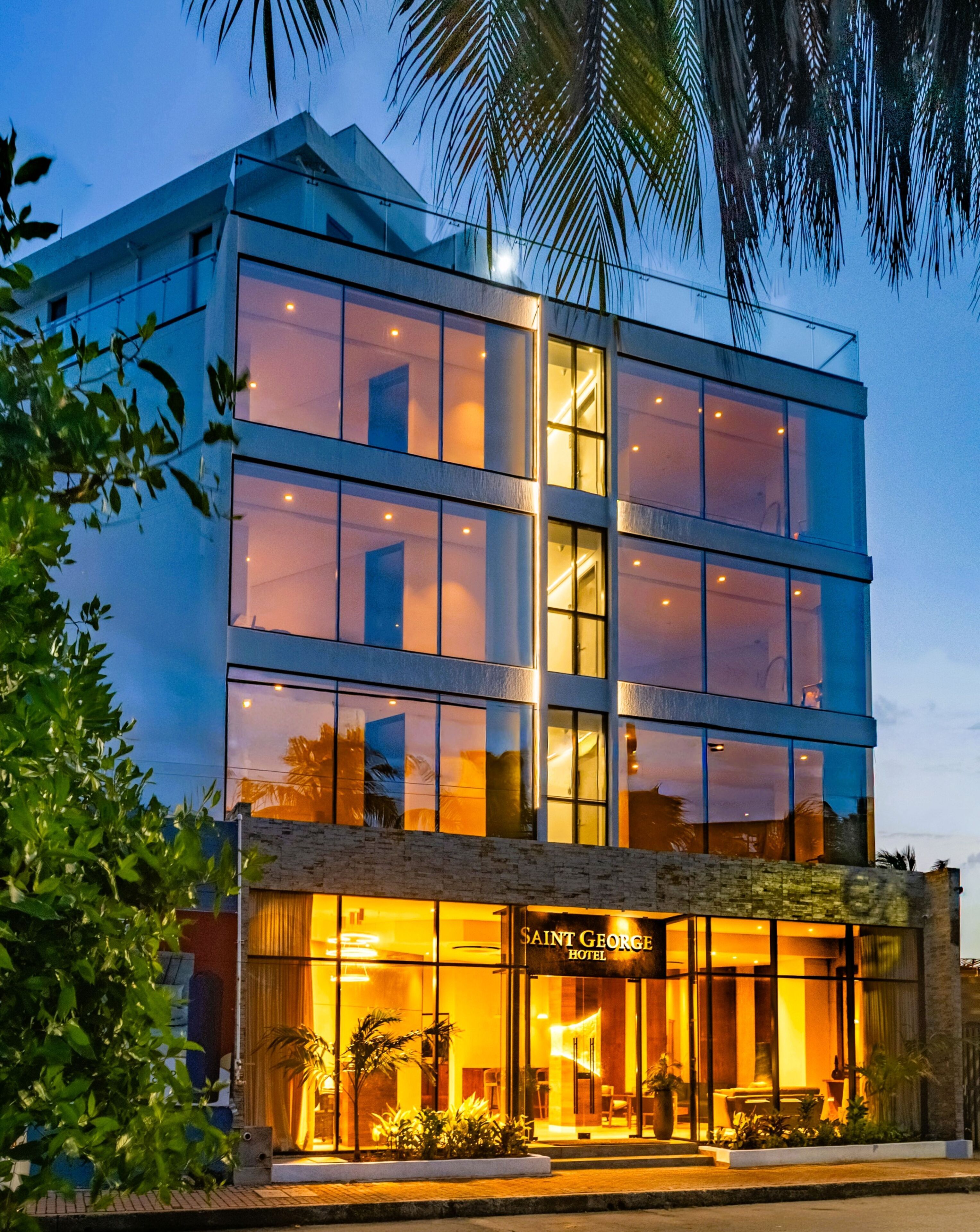 A modern hotel with multiple floors, large windows, and a well-lit entrance.