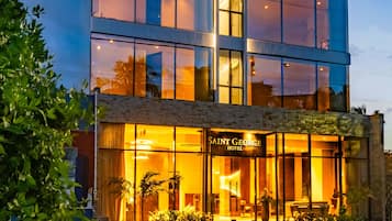 A modern hotel with multiple floors, large windows, and a well-lit entrance.