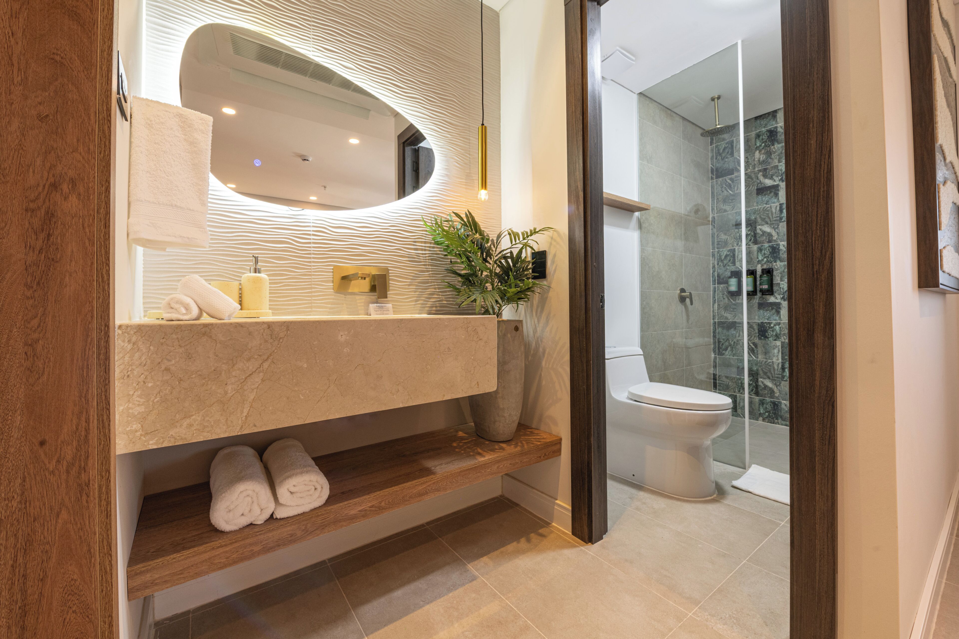 Une salle de bain moderne équipée d’un lavabo intégré, d’un miroir, d’une douche et de toilettes.
