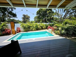 A swimming pool with a wooden deck, surrounded by lush greenery and a white fence. - Papi's Place: Private Pool Villa in Playa Negra, Costa Rica (Cahuita)
