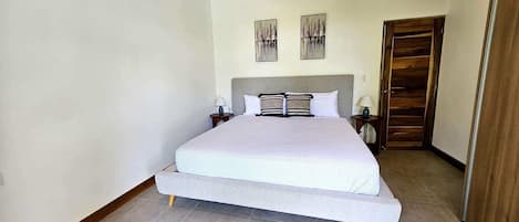 A bedroom with a bed, nightstands, a wooden ceiling, and a wardrobe.