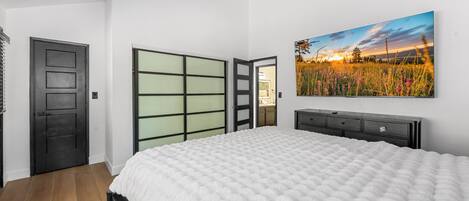 A bedroom with a bed, a wardrobe, a door, and a painting on the wall.