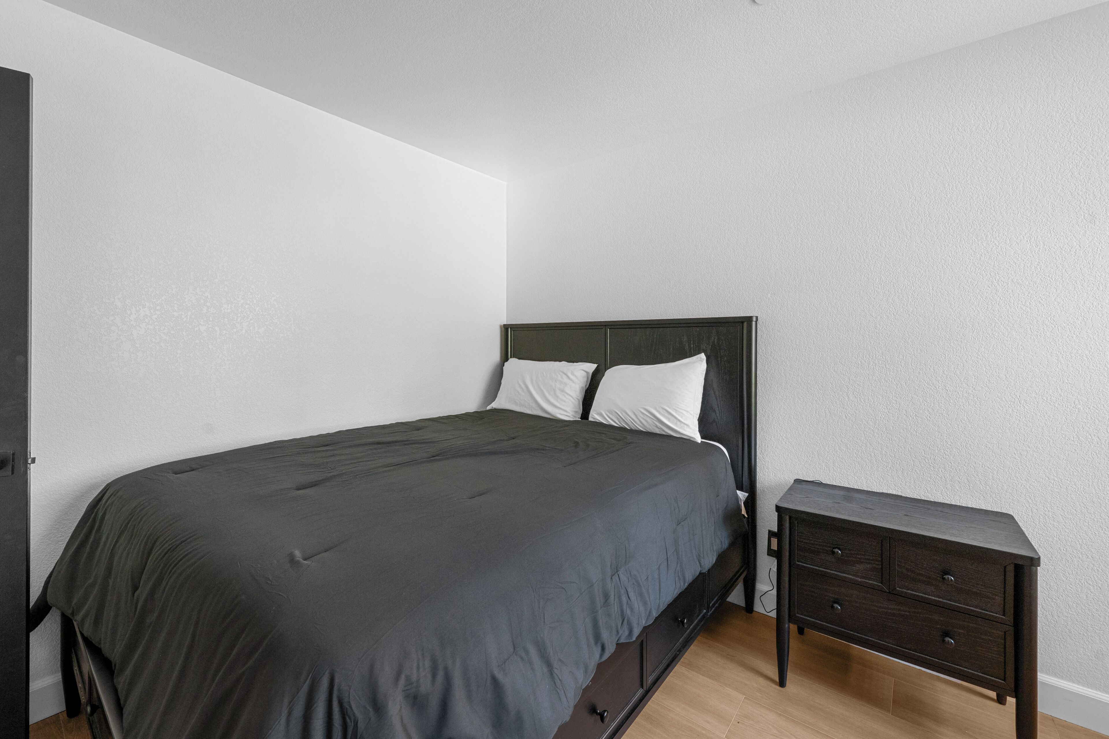 A bedroom with a single bed, a nightstand, and a dresser.
