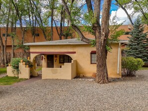 A building with a small porch, a tree in front, and a gravel driveway.