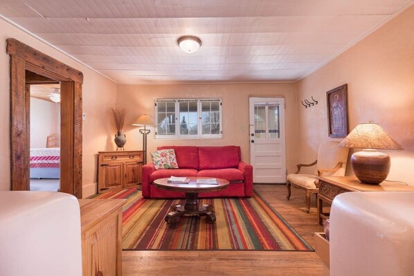 A cozy living room with a red sofa, a coffee table, a lamp, and a patterned rug.
