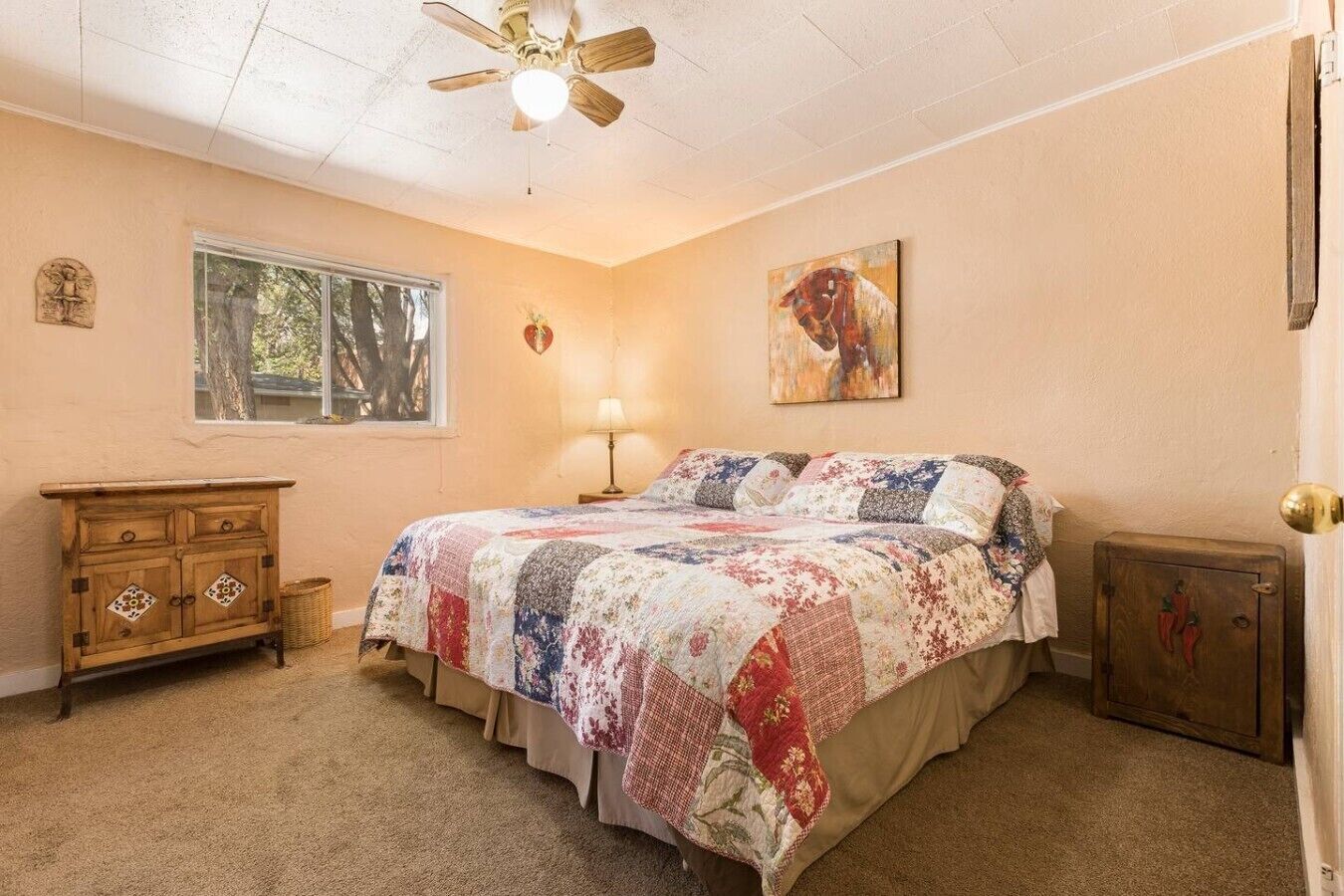 A bedroom with a bed, a dresser, a lamp, and a painting on the wall.