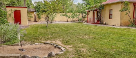 Un quartier résidentiel avec une pelouse bien entretenue, un petit abri de jardin et une maison avec un toit rouge.