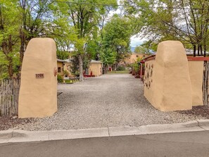 A gated entrance with a gravel path leading to a row of buildings.
