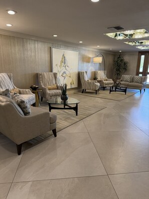 A spacious living room with a large abstract painting, multiple seating areas, and a modern chandelier. - Spacious Contemporary -- Striking Mountain Views 2B/2BA in Coveted Desert Island (Rancho Mirage)