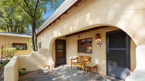 A building with a stucco exterior, a wooden bench, a dog, and a small garden area.