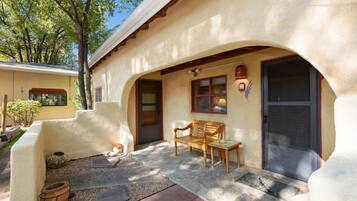 A building with a stucco exterior, a wooden bench, a dog, and a small garden area.