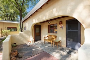 A building with a stucco exterior, a wooden bench, a dog, and a small garden area.