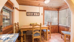 A cozy dining area with a wooden table and chairs, a tiled floor, and a window with blinds.