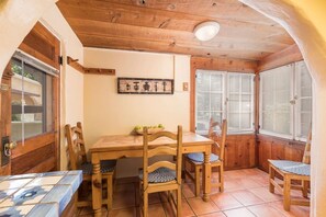A cozy dining area with a wooden table and chairs, a tiled floor, and a window with blinds.
