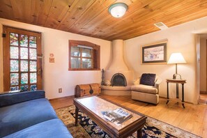 A cozy living room with a fireplace, a sofa, a coffee table, and a lamp.