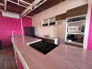 A kitchen with a central island, a refrigerator, and a microwave on a shelf. - Spacious & Cozy Suites with pool (Cabo San Lucas)