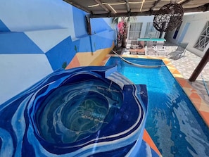 A swimming pool with a slide, surrounded by a colorful geometric wall design. - Spacious & Cozy Suites with pool (Cabo San Lucas)