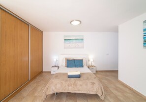 Ein Schlafzimmer mit einem Bett, Nachttischen, einem Kleiderschrank und einem Bild an der Wand.