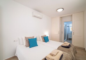 A bedroom with two beds, a wardrobe, an air conditioning unit, and a bathroom visible through an open door. - Large 4 Bedroom Villa Featuring Hot Tub, Private Pool & Air Con (Playa Blanca)