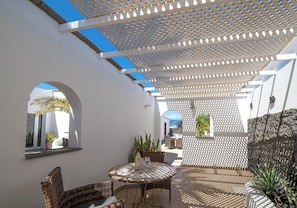 An outdoor patio area with a round table and chairs, a pergola overhead, and a view of the sea. - Large 4 Bedroom Villa Featuring Hot Tub, Private Pool & Air Con (Playa Blanca)