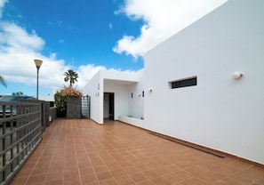 A modern building with a white exterior, a tiled patio area, and a clear sky. - Relaxing & Private 3 Bedroom & 3 Bathroom Villa (Playa Blanca)