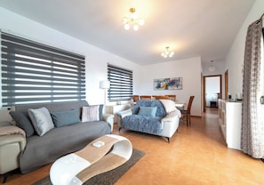 A modern living room with two sofas, a coffee table, and a dining area with chairs. - Relaxing & Private 3 Bedroom & 3 Bathroom Villa (Playa Blanca)
