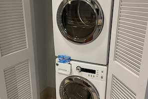 A stacked washer and dryer unit with a control panel and a detergent dispenser.
