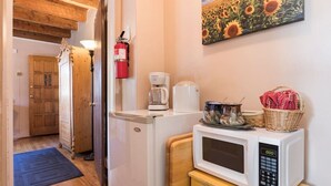 A kitchen with a refrigerator, microwave, coffee maker, and a painting of sunflowers on the wall.