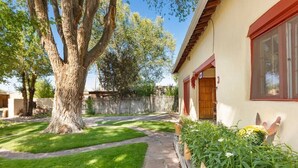 A residential property with a stone pathway leading to a wooden door, surrounded by a well-maintained lawn and a large tree.