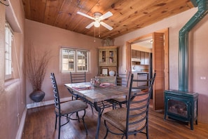 A dining area with a wooden ceiling, a table set for two, and a vintage stove.