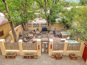 A courtyard with a hot tub, seating area, and a wooden fence.